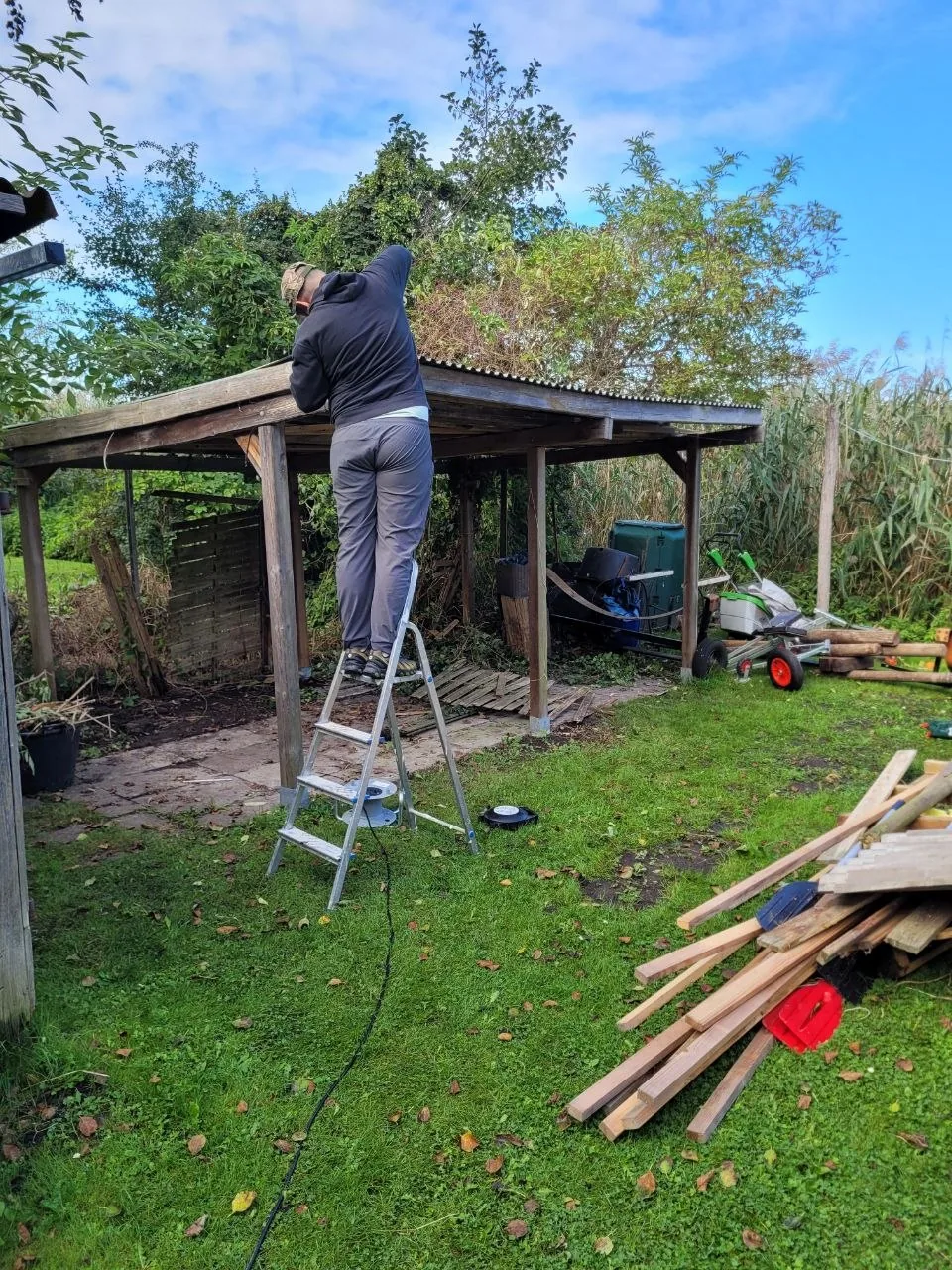 Mitarbeiter von B&B Service baut das Dach eines alten Gartenhauses zurück